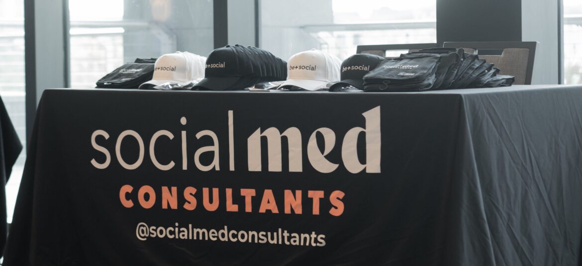 Social Med Consultants branded table display with hats and merchandise client booth