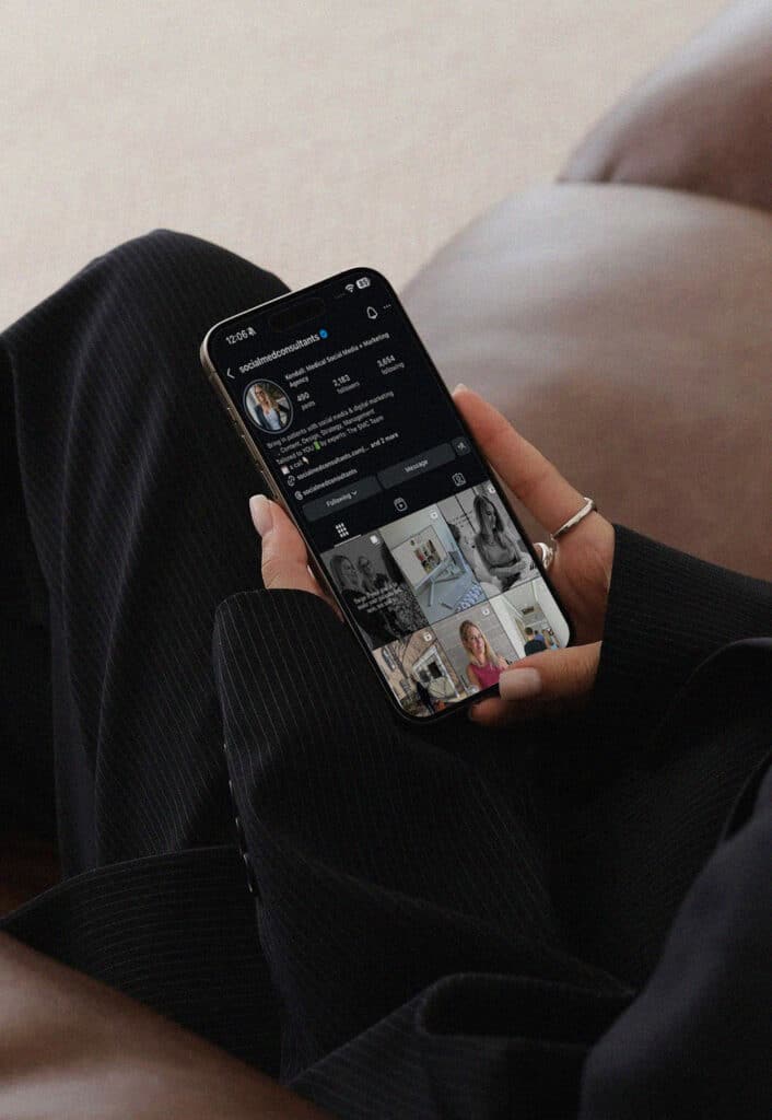 Person holding smartphone displaying the Social Med Consultants Instagram profile page
